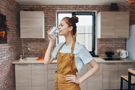 Домохозяйка пьёт воду на кухне