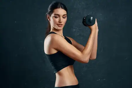 Спортивная женщина со стройной фигурой тренируется на темном фоне