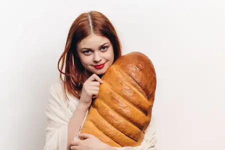 Эмоциональная женщина с батоном хлеба в руках, макияжем, рыжая модель