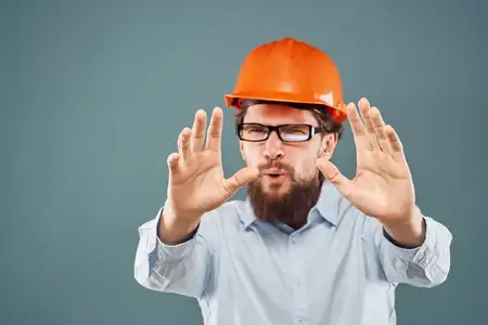 Эмоциональный мужчина в очках и оранжевой каске работает в промышленности