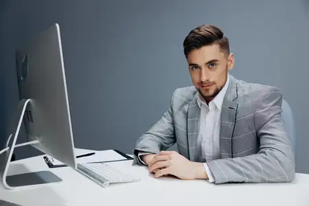 Менеджер работает за компьютером в офисе на сером фоне