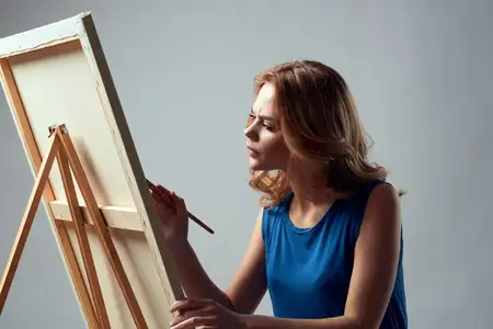 Женщина-художница с кистью и красками у мольберта, искусство, хобби, светлый фон