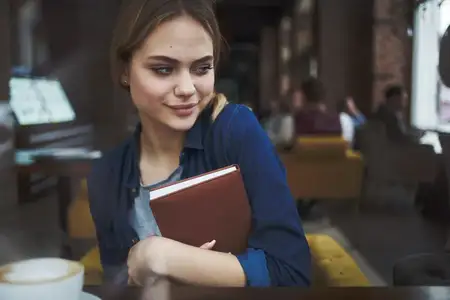 Деловая женщина с книгой в руках и чашкой кофе в кафе, ведущая активный образ жизни
