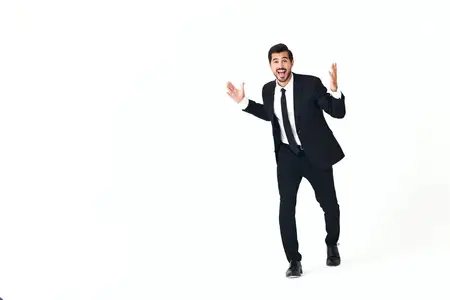 Мужчина в деловом костюме улыбается, обнажая зубы, бежит и прыгает с открытым ртом, выражая радость и удивление