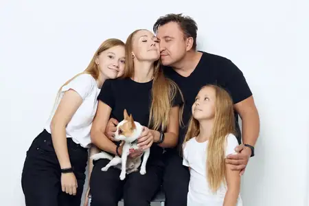 На студийном изолированном фоне счастливая дружная семья обнимается