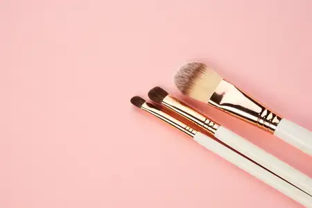 Кисти для теней для век, коллекция профессиональной косметики и аксессуаров на розовом фоне