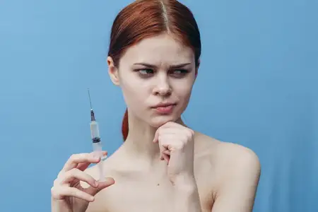 Шприц в руке женщины на голубом фоне