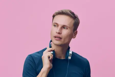 Задумчивый мужчина держит наушники около шеи