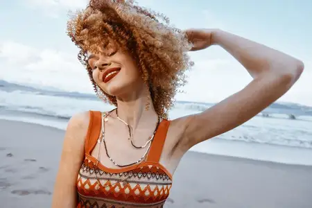 Улыбающаяся женщина с рюкзаком наслаждается счастливым отпуском на пляже