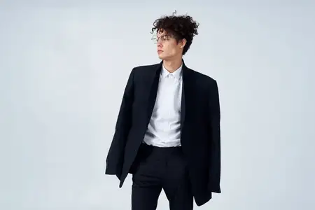 Деловой мужчина в костюме и очках, с кудрявыми волосами, в студийной fashion-съемке