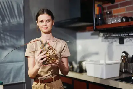 Женщина держит птицу на кухне на фоне клетки при естественном освещении