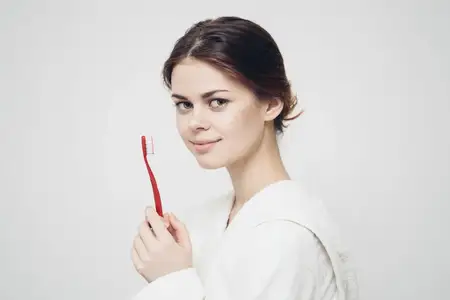 Весёлая женщина в халате с зубной щёткой, утренняя гигиена и забота о зубах