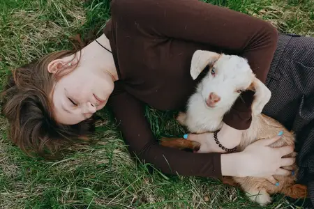 Женщина отдыхает на траве на природе с козлёнком, демонстрируя привязанность, доверие и нежное взаимодействие