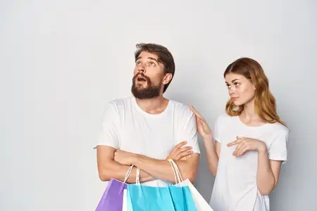Молодая пара с сумками в руках наслаждается весёлым шопингом и распродажей