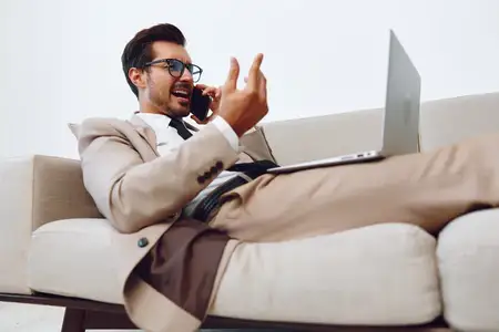 Успешный бизнесмен в очках и деловом костюме сидит в современном офисе
