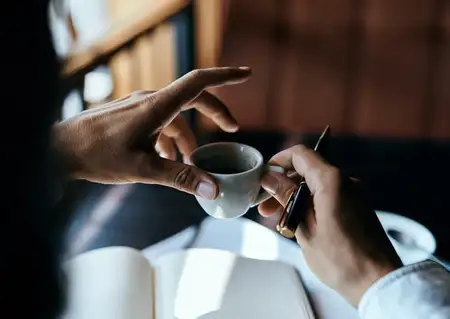 Бизнесвумен в кафе с книгой на столе, документами и чашкой кофе