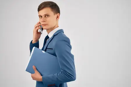 Мужчина в костюме с синей папкой разговаривает по телефону