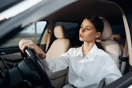 Женщина сидит на водительском сиденье автомобиля