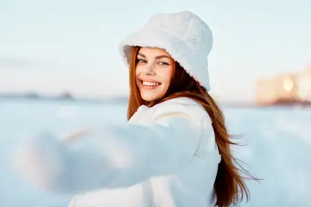 Симпатичная женщина улыбается, прогуливаясь в белом пальто, передавая зимнее настроение и стиль жизни