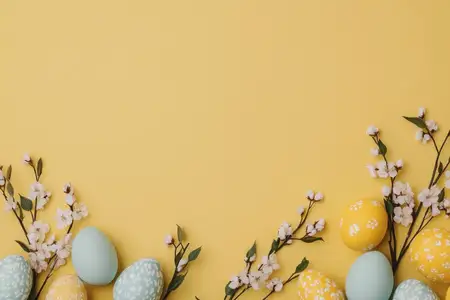 Праздничная пасхальная композиция с разноцветными яйцами и весенними цветами на ярком желтом фоне