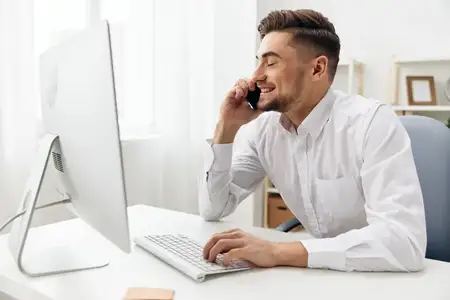 Привлекательный мужчина в белой рубашке работает в офисе за компьютером