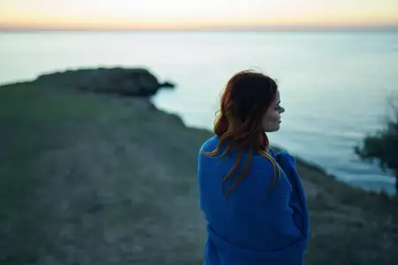 Женщина в синем пледе в горах, на природе, наслаждается свежим воздухом