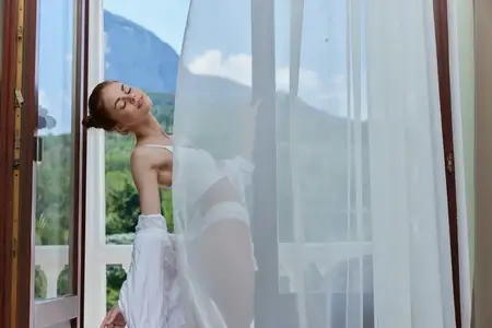 Подтянутая женщина в нижнем белье стоит на балконе, откуда открывается красивый вид из окна, без ретуши