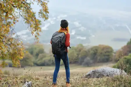 Веселая женщина-туристка в горах наслаждается природой, отдыхом, весельем и свежим воздухом