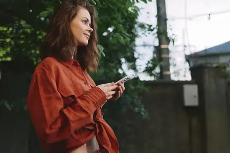 Портрет женщины, наслаждающейся моментом на улице со смартфоном в руке