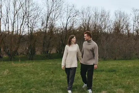 Сцена образа жизни пары в поле, наслаждение природой, повседневная мода, расслабленные позы, легкий ветерок, приглушенная палитра, обширный пейзаж, интимный момент, связь в обстановке на открытом…