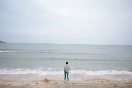 Красивая женщина одна у океана в облачную погоду