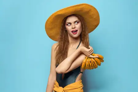 Женщина в купальнике и шляпе с экзотическими фруктами, летнее веселье на синем фоне