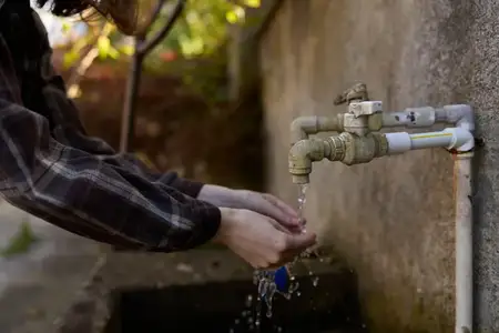 Руки моются под краном на улице, вода мягко разбрызгивается