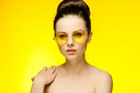 Веселая женщина с обнаженными плечами в желтых очках, собранные волосы, студия