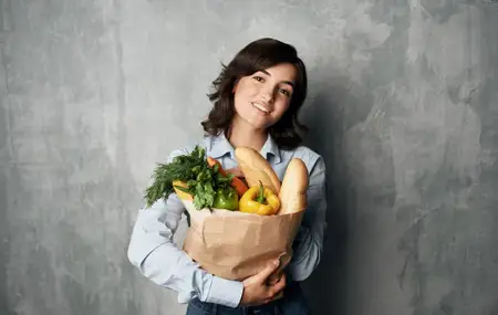 Жизнерадостная брюнетка с пакетом продуктов, доставка покупок