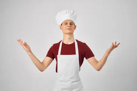 Мужчина-повар в униформе работает на кухне ресторана, занимаясь приготовлением пищи