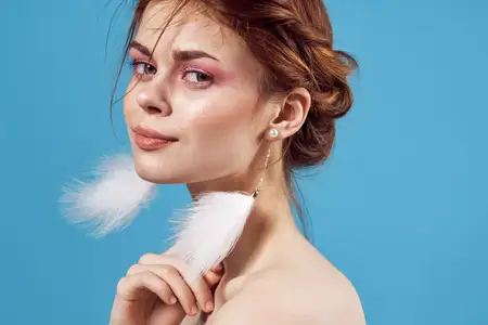 Женщина с обнаженными плечами, модные украшения, серьги на синем фоне