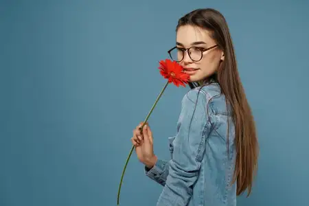 Симпатичная брюнетка с красным цветком позирует в атмосфере гламура и романтики