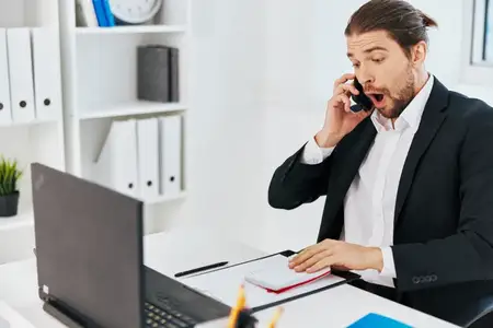 Мужчина испытывает эмоции во время работы за ноутбуком, общаясь с начальником
