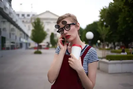 Женщина на прогулке на открытом воздухе, во время отпуска, держит в руке стакан с напитком