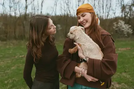 Непринужденный момент между друзьями в парке демонстрирует привязанность к игривому щенку, подчеркивая образ жизни, дружеское общение и естественную радость среди зелени и открытого пространства в…