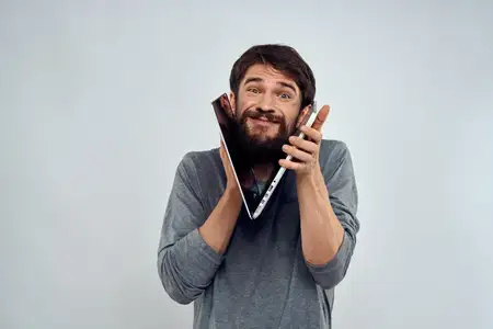Эмоциональный мужчина держит ноутбук