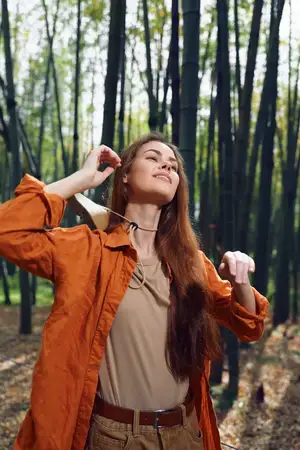 Женщина в лесу, на ней шляпа, осеннее солнце и счастье
