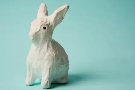 Праздничная игрушка — белый кролик на голубом фоне с пастельными тонами, посвящённая Пасхе