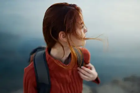 Женщина с рюкзаком в горах на открытом воздухе у моря, вид со спины, кадрированный снимок модели