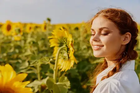 Улыбающаяся женщина рядом с подсолнухом