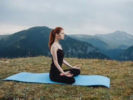 Спортивная женщина занимается йогой и медитацией в горах, наслаждаясь природой и свежим воздухом