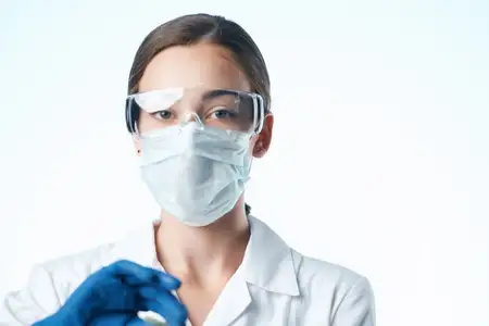 Лаборант в белом халате и медицинской маске проводит исследования и анализ