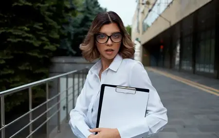 Деловая женщина в очках с документами возле здания на улице