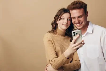 Счастливая молодая пара обнимается и делает селфи на смартфон